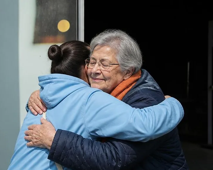 Eine ältere Frau umarmt herzlich eine junge Frau