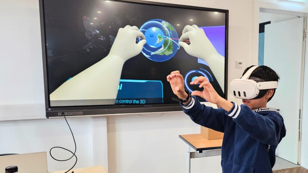Junge mit VR-Brille dreht mit Handbewegungen eine virtuelle Erdkugel beim Techniktag in Baesweiler